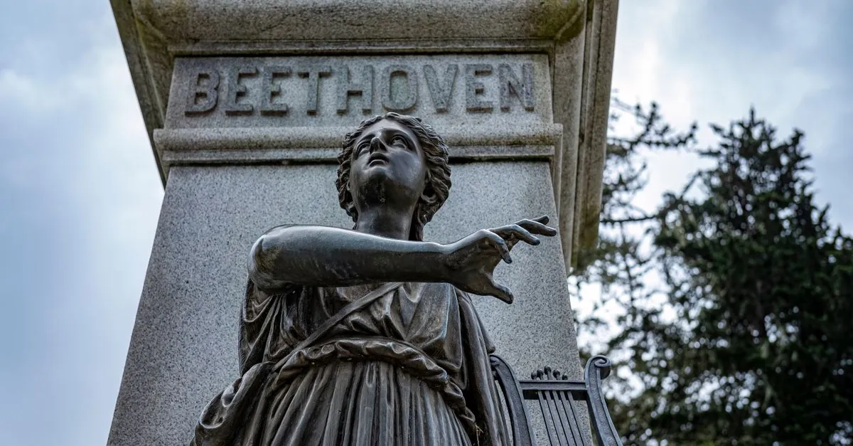 Una escultura detallada de una figura sosteniendo una lira bajo el nombre de Beethoven, rodeada de árboles.