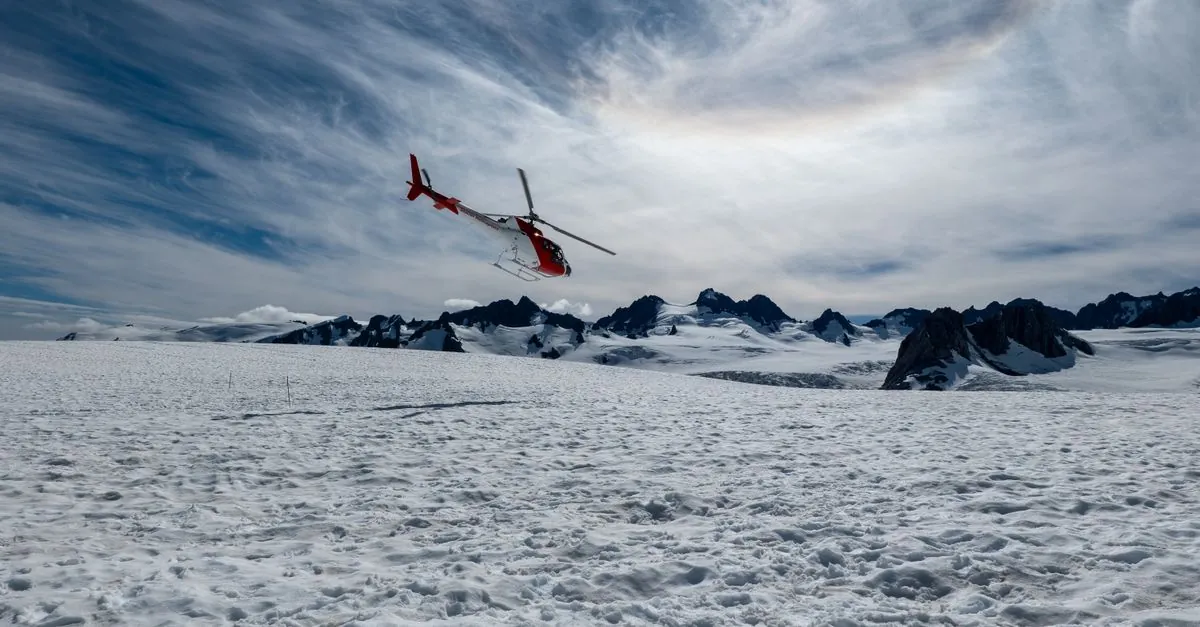 Helicóptero sobrevolando el glaciar nevado Fox con un impresionante telón de fondo montañoso en Nueva Zelanda.