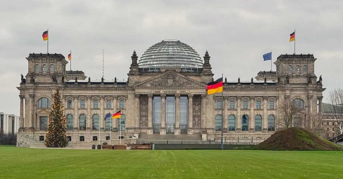 Edificio del Reichstag en Berlín, Alemania, con banderas y árbol de Navidad en invierno.