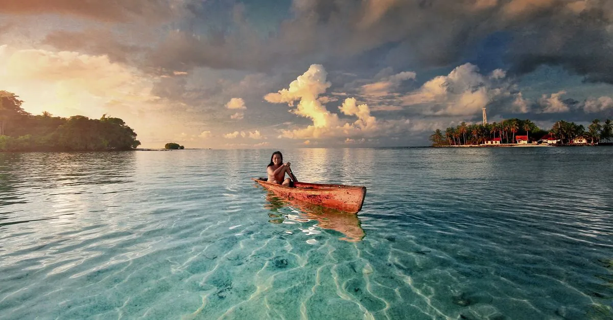 Un sereno paseo en canoa por las aguas cristalinas de Indonesia durante el atardecer, mostrando la belleza natural.